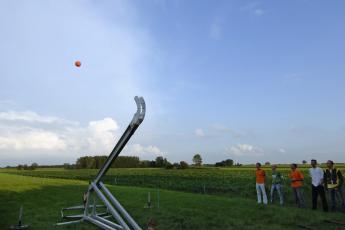 Met een zwaai werpt de katapult een bowlingbal ongeveer 40 meter ver weg.