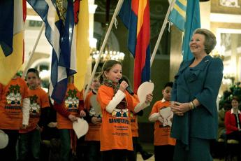 Koningin Beatrix luistert naar een scholiere.