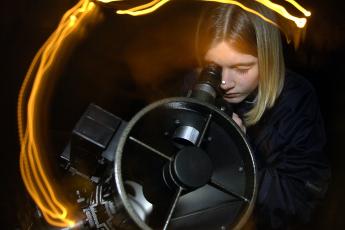 Lisanne Btger (13) tuurt door een telescoop naar de donkere hemel boven Heerenveen.