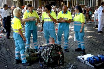 Ambulancepersononeel bij een militair die aan medische apparatuur ligt.