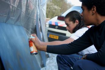 gent in opleiding Naima (r.) en Chefrany werken geconcentreerd aan een graffitikunstwerk.