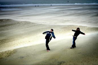 Twee jongeren genieten van de storm op het strand van Vlissingen.