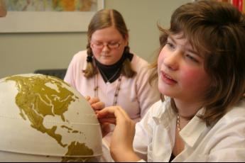 Henrit de Weerd (13) leest met haar vingers een wereldbol waarin de landen met braille zijn aangegeven.