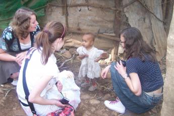 Eline, Elizabeth en Janine met een kindje uit een sloppenwijk.