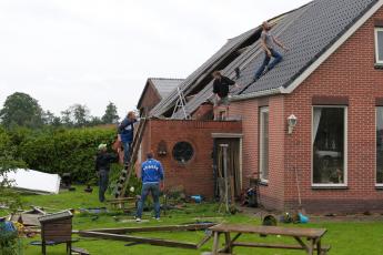 Bewoners leggen dakpannen terug.