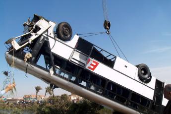 Reddingswerkers takelen de bus uit het kanaal.