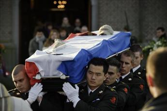 Militairen dragen zaterdagmiddag de kist de kerk uit.