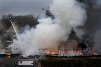 De brandweer bestrijdt met groot materieel de brand.