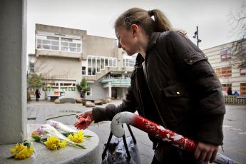 Een meisje legt bloemen neer in nagedachtenis van de doodgestoken overblijfwacht in Amsterdam.