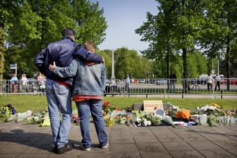 Mensen zoeken steun bij elkaar en leggen bloemen.