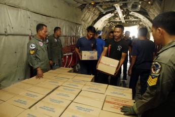 Indonesische soldaten halen hulppakketten uit een vliegtuig.